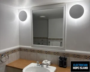 A modern bathroom with a large mirror, sink, and elegant countertop, featuring minimalist design